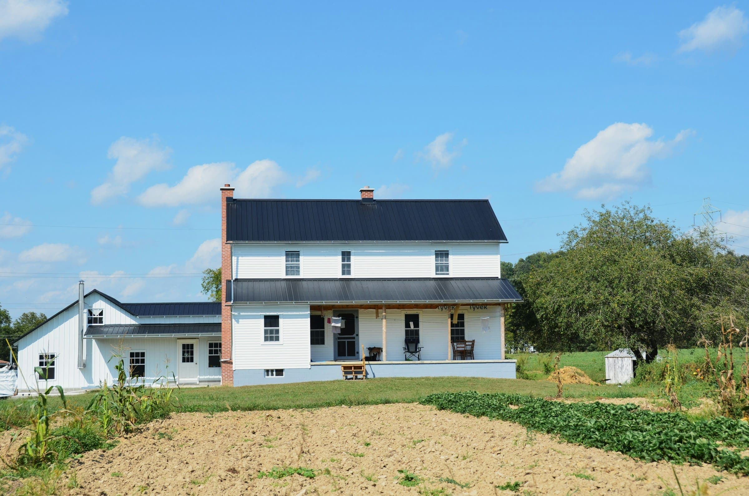 White farmhouse with a black standing-seam metal roof