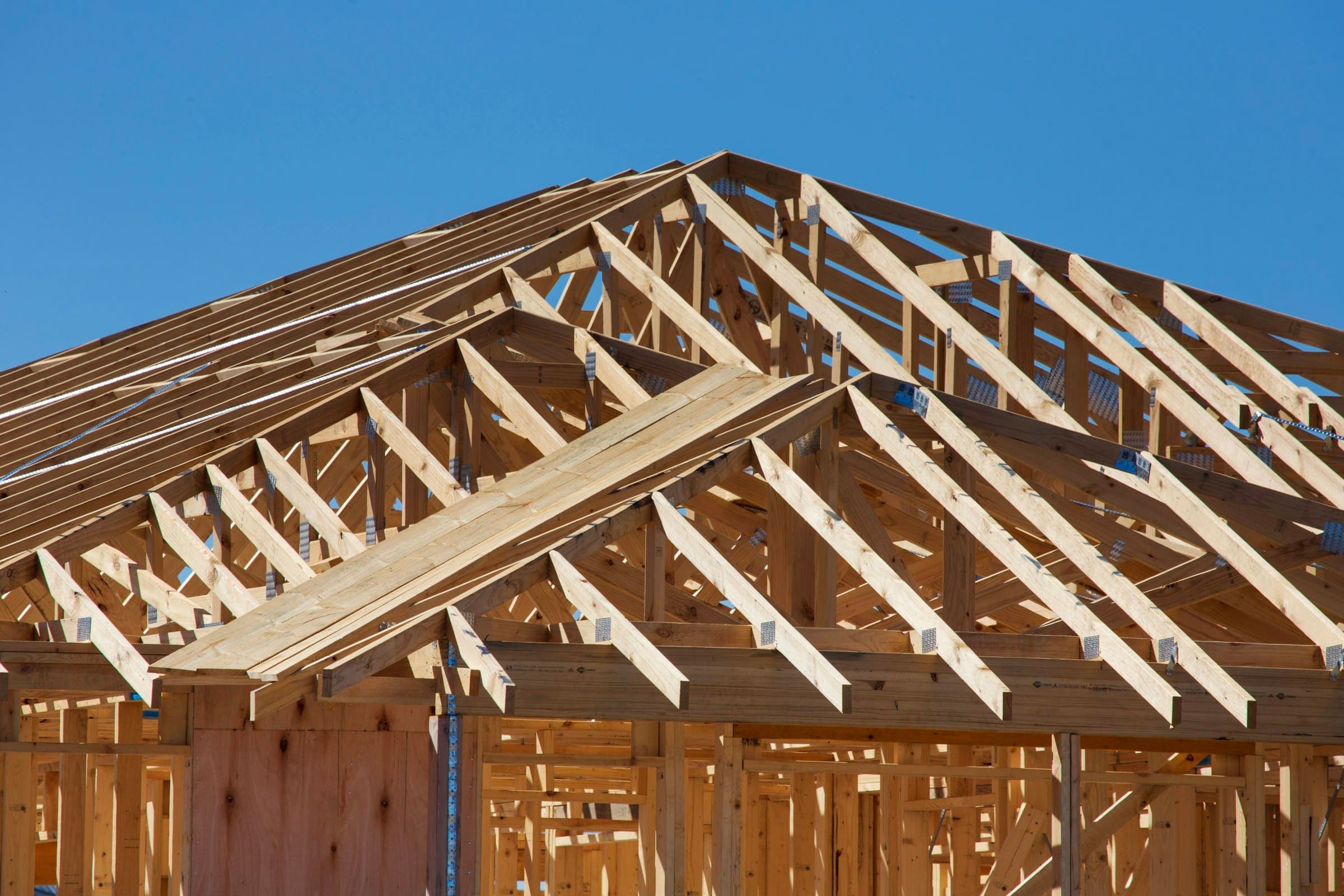 New wood roof trusses framed against a blue sky