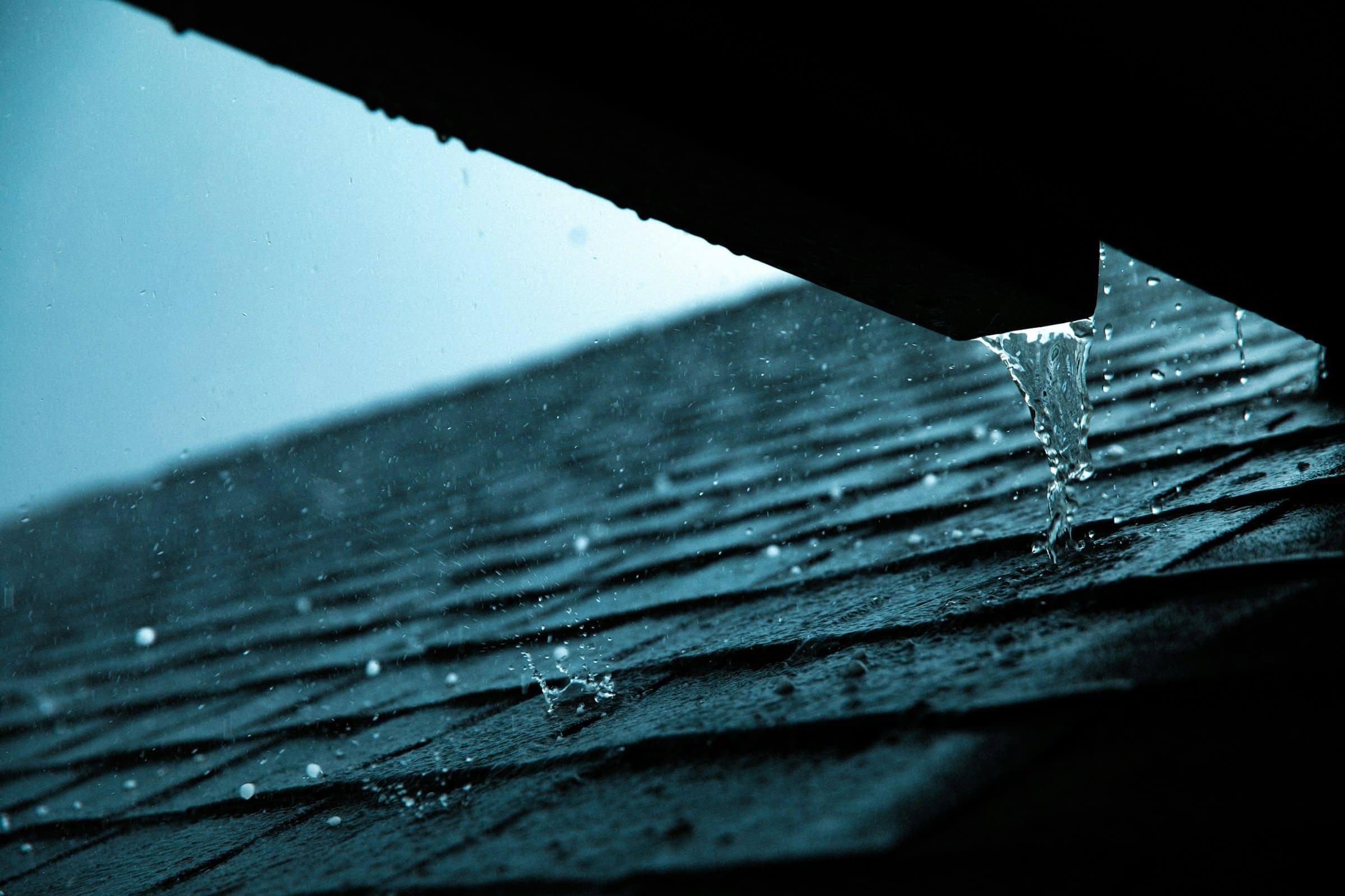 Rainwater running off the edge of a shingle roof