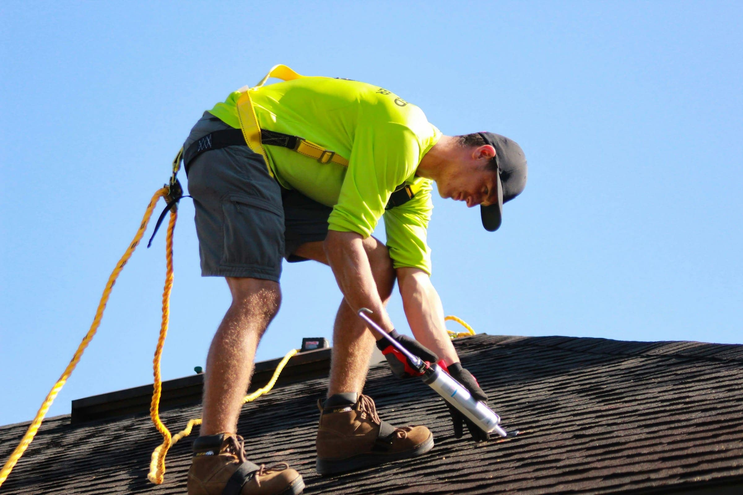 Roofer sealing a shingle roof detail with a caulk gun